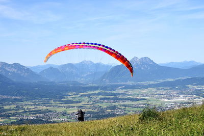 Person paragliding over mountain against sky