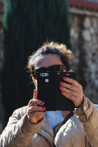 Mature woman in warm clothing using mobile phone while standing outdoors