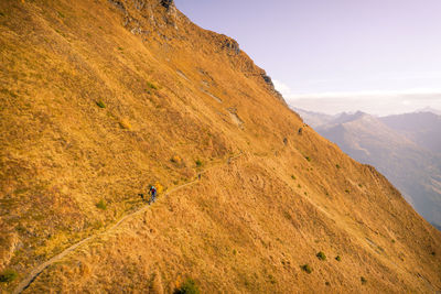 Man cycling on mountain road against sky