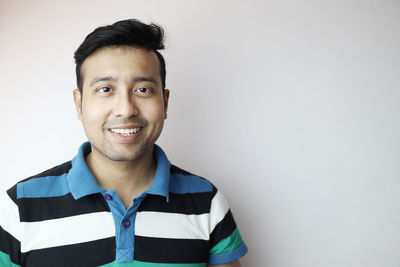 Portrait of smiling young man against wall