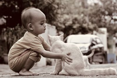 Portrait of a cute boy playing with his cat on the roadside in front of his house