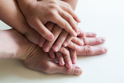 Cropped image of family hands stacking on white table