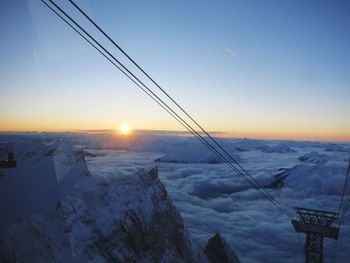 Snow covered landscape against sky during sunset