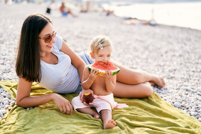 Side view of woman sitting on sand at beach