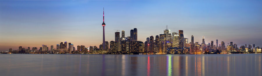 Illuminated modern buildings in city against sky