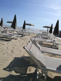 Deck chairs on beach against sky