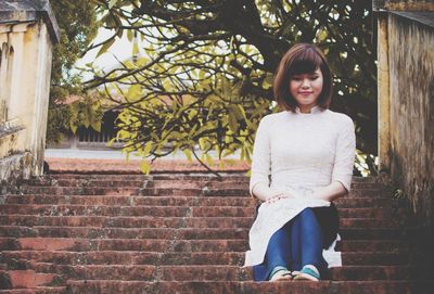 Portrait of smiling young woman standing against brick wall