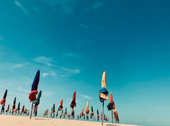 Closed parasols at beach against blue sky during summer