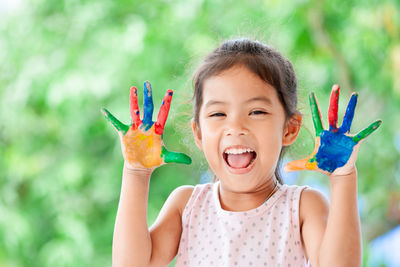 Close-up portrait of happy girl with painted hands