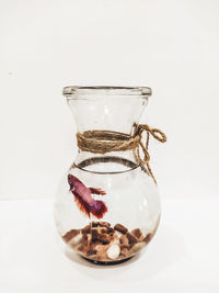 Close-up of glass jar on table against white background