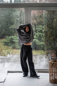 Young woman standing against window at home