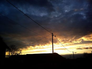 Low angle view of silhouette trees against dramatic sky