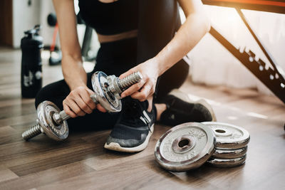 Midsection of man holding dumbbell in gym