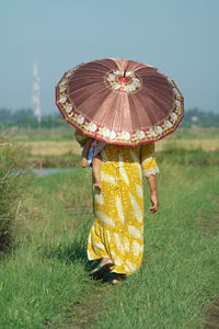 Rear view of woman standing on field