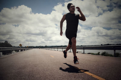 Full length of man running on road against sky