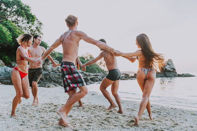 Full length of people on beach against sky