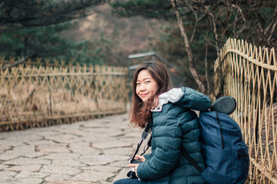 Portrait of smiling young woman sitting on footpath