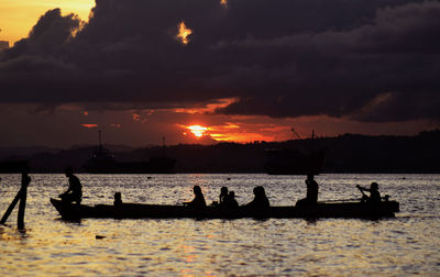 Silhouette of boat in sea at sunset