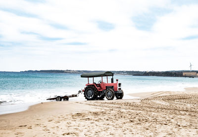 Tractor on beach against sky