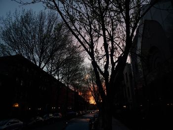 Illuminated street amidst buildings in city at dusk