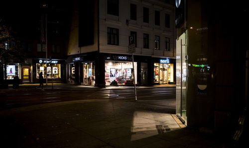 Illuminated street amidst buildings at night