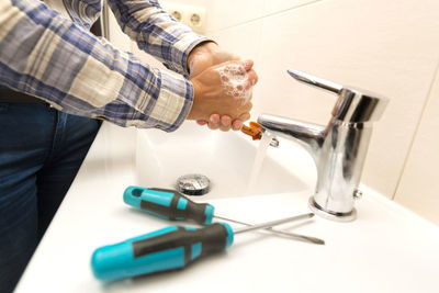 Midsection of woman washing hands at bathroom sink