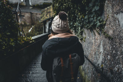 Rear view of woman standing against wall