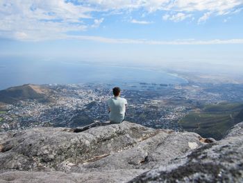Man sitting by sea against sky