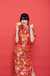 Portrait of a smiling young woman holding red background