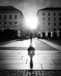 Rear view of person walking on street amidst buildings in city