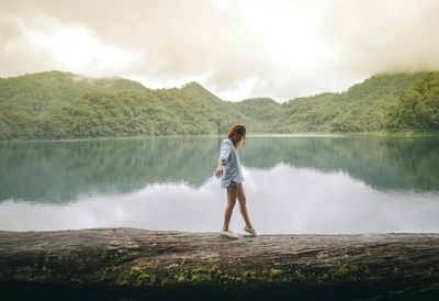 Side view of man walking by lake against sky