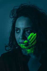 Woman with neon face paint against black background