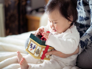 Close-up of mother helping daughter in unwrapping christmas gift