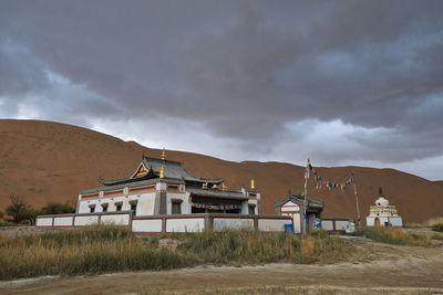 Built structure on field by buildings against sky