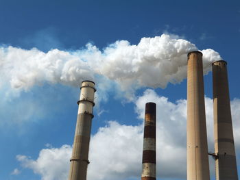 Low angle view of industrial building against cloudy sky