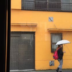 Rear view of woman with umbrella walking in office building