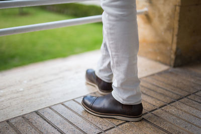 Low section of fashionable man wearing shoes while standing on floor