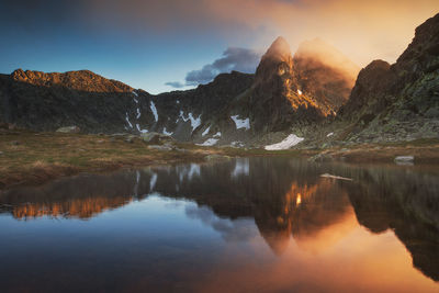 Scenic view of lake by mountains against sky during sunset