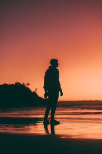 Silhouette woman walking at beach during sunset