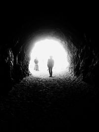 Rear view of silhouette people walking in illuminated tunnel