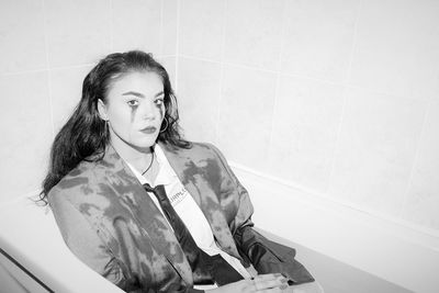 Portrait of depressed woman sitting in bathtub at home