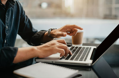 Midsection of man using laptop on table