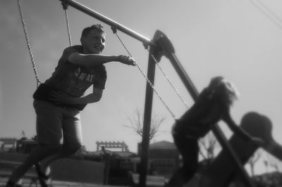 Low angle view of girl playing on rope against sky