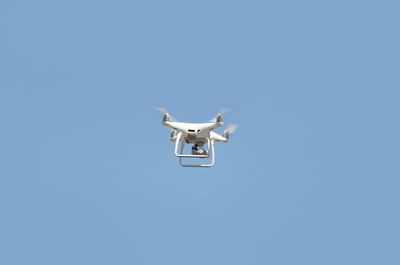 Low angle view of airplane flying against clear blue sky