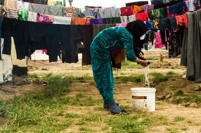 Side view of woman drying laundry on clothesline