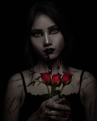 Close-up portrait of spooky young woman holding red rose against black background