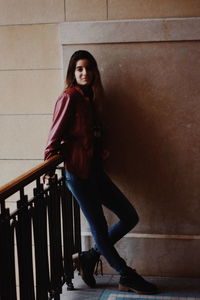 Portrait of smiling young woman standing against railing