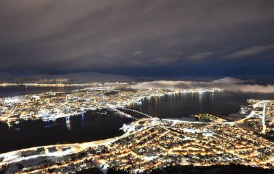 High angle view of illuminated buildings by sea against sky