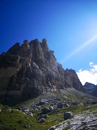 Low angle view of rocks against clear blue sky