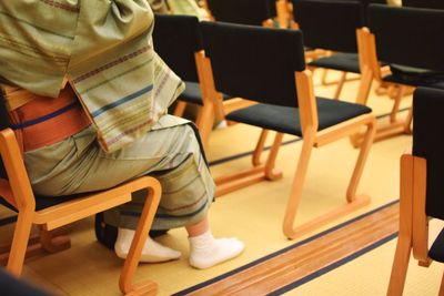 Low section of woman wearing kimono while sitting on chair